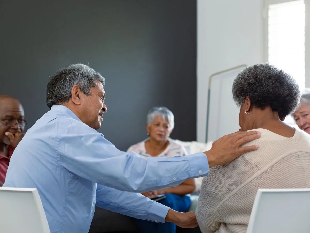 Senior caregivers sitting around a table offering eachother emotional support